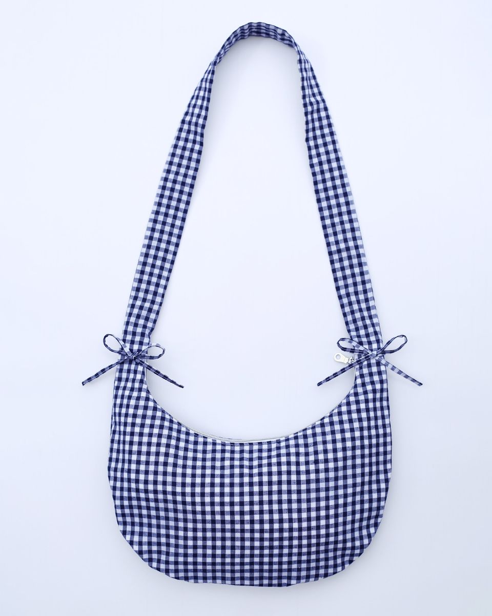 The Drawstring Crescent Bag with its strap long (flat).
