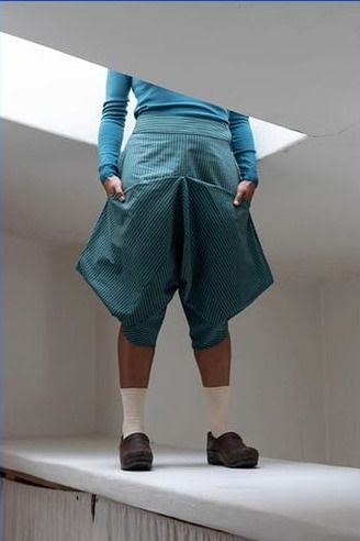 Front view of a person standing with their head in a skylight wearing teal Leija trousers