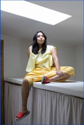 Person in all yellow sitting on a white surface. One leg dangles over the edge.