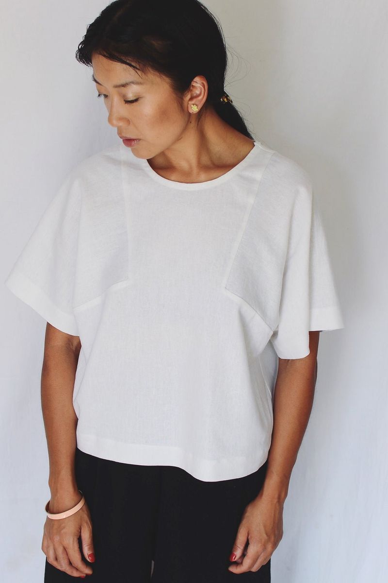 Front shot of model wearing top made in white fabric