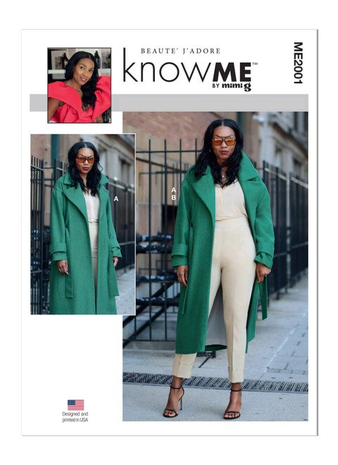A woman wearing an oversized green wool coat with large lapels, belt, and sleeve bands. She is wearing slim cream trousers and a cream long-sleeved shirt underneath. 